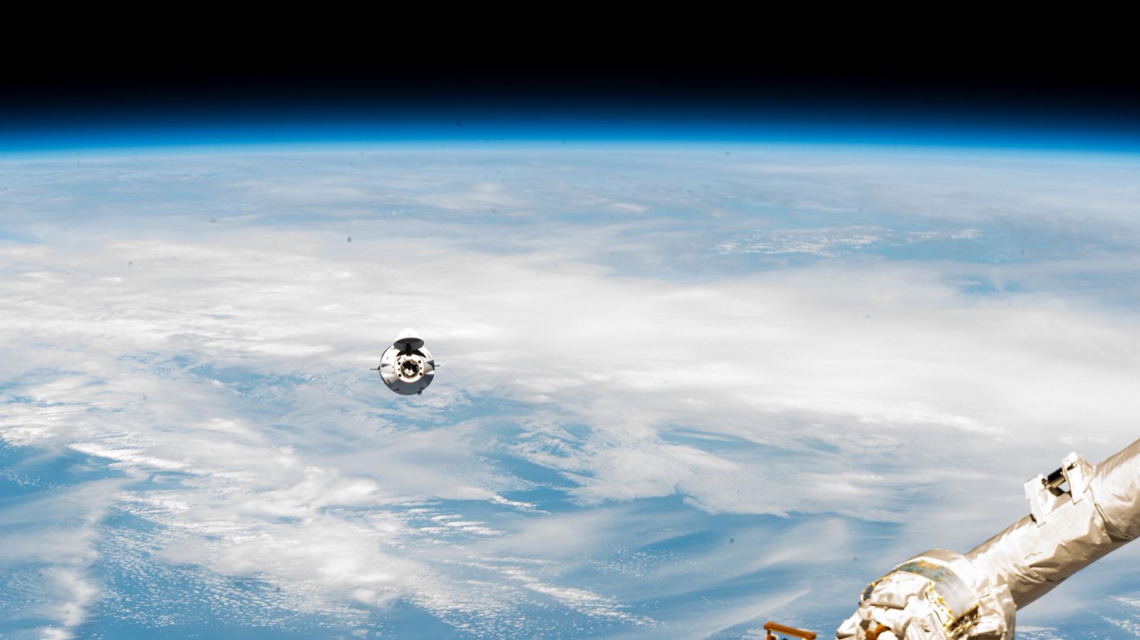 A cargo capsule on approach to the station high above clouds