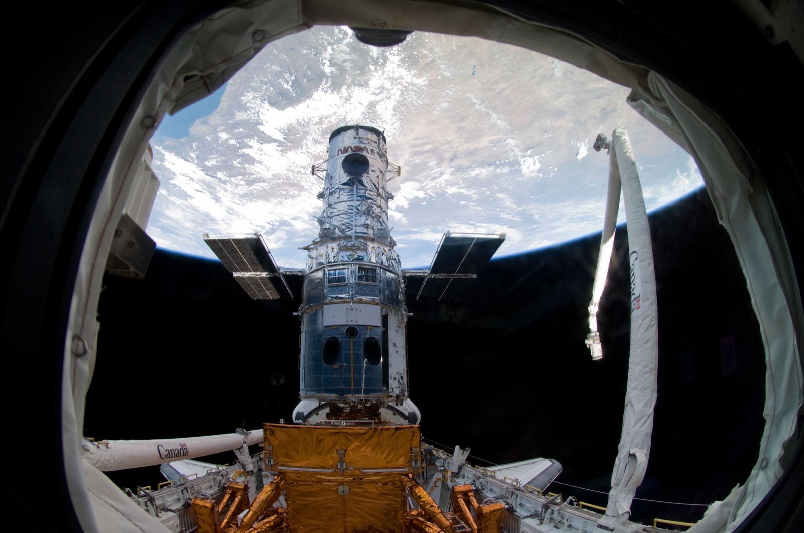The Hubble Space Telescope berthed in the shuttle cargo bay during a servicing mission, Earth behind