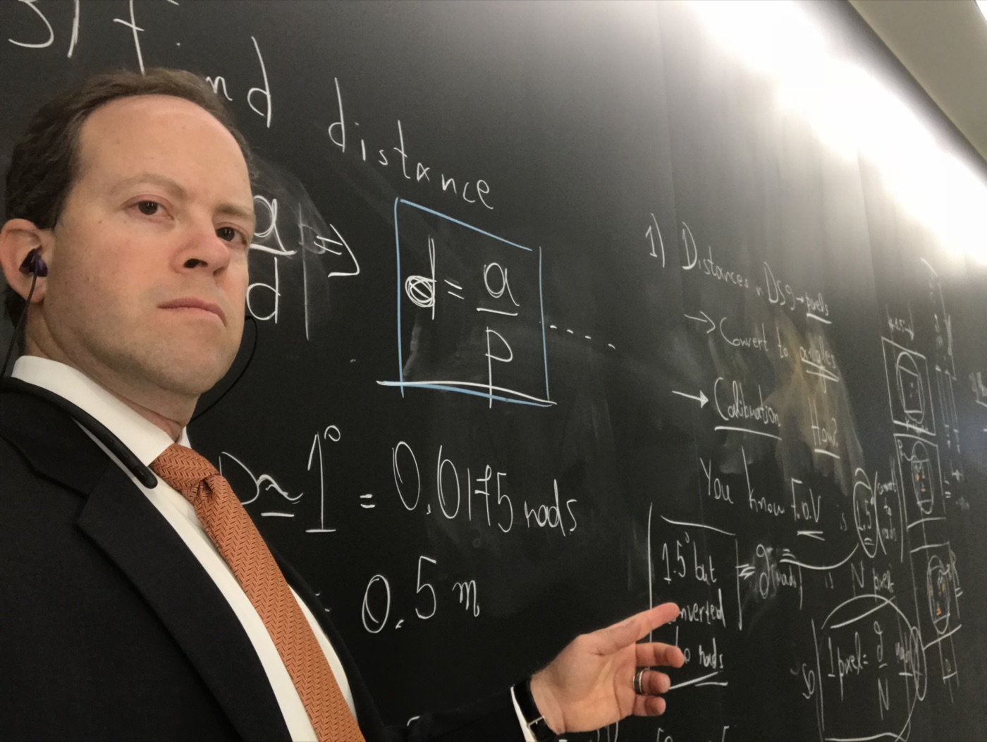 Russ Rosenzweig at a blackboard covered in equations for angular size, field of view and camera calibration