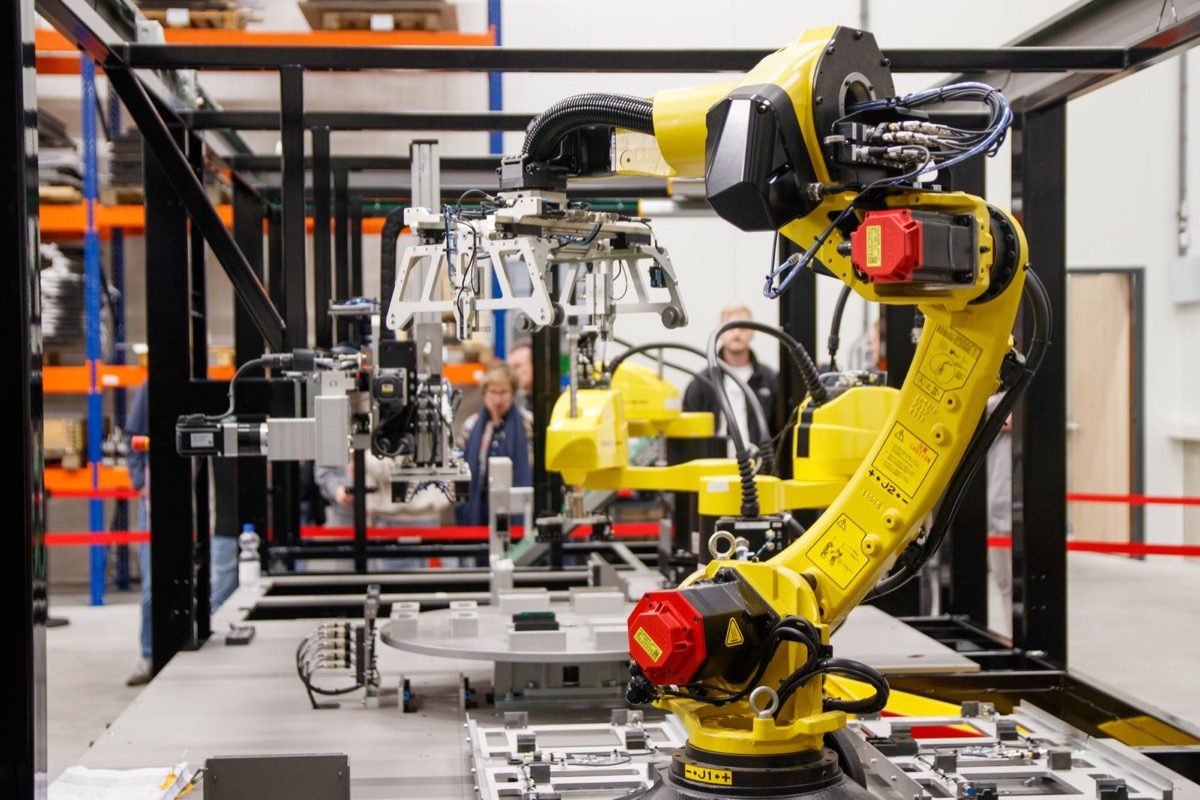 A yellow six axis industrial robot in an integration cell