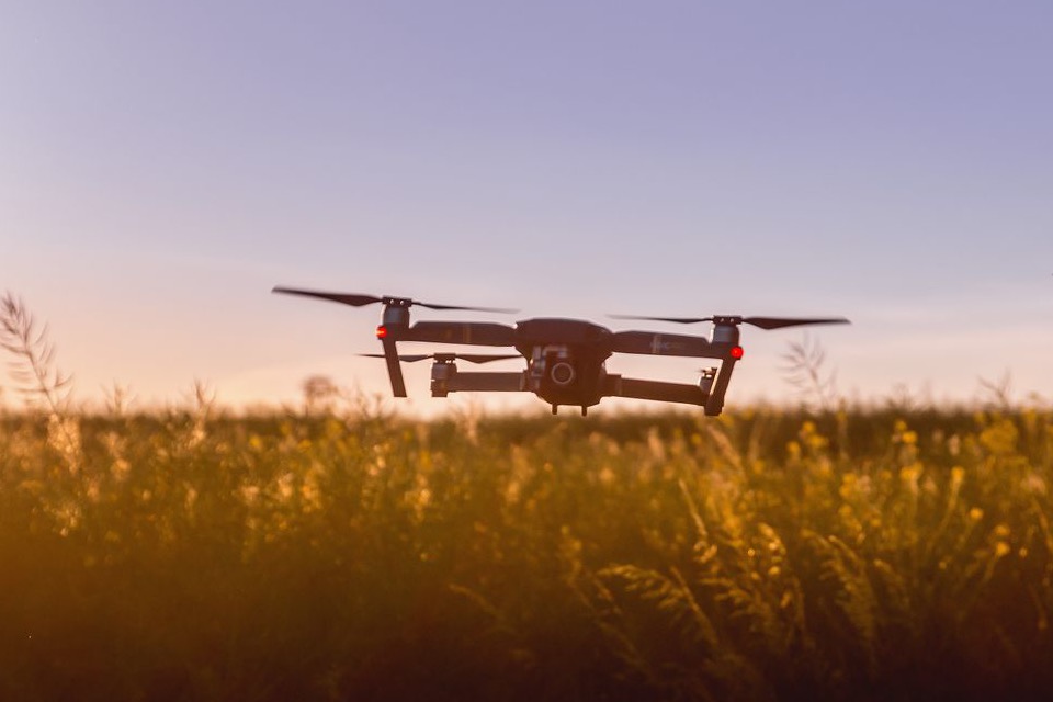 A survey drone hovering over a field at dusk